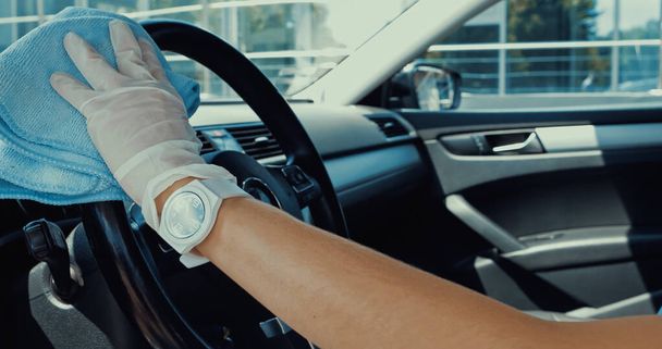 cropped view of woman in latex glove wiping steering wheel with rag - Foto, Imagen