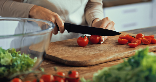 vista recortada de la mujer cortando tomates cherry en la tabla de cortar  - Foto, Imagen