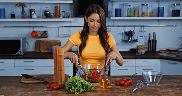 jeune femme mélangeant salade fraîche dans la cuisine  - Photo, image