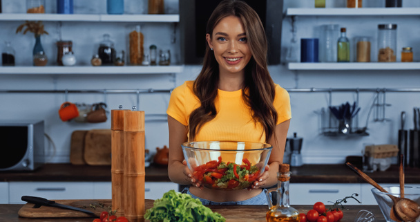 fröhliche Frau hält Schüssel mit frischem gemischten Salat  - Foto, Bild