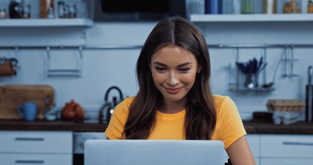 brunette young freelancer smiling while using laptop  - 写真・画像