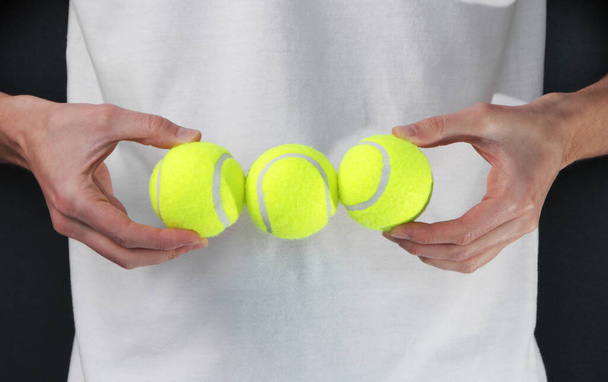Ένας άντρας με αθλητική άσπρη στολή του τένις έχει αρχίδια. Παίζοντας τένις. κοντινό πλάνο - Φωτογραφία, εικόνα