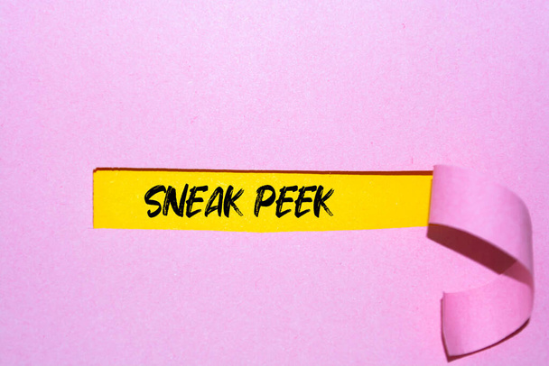 SNEAK PEEK parola scritta sotto il concetto di carta strappata Immagine. - Foto, immagini