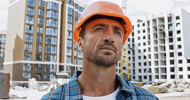 Handsome builder looking away on construction site - Photo, Image