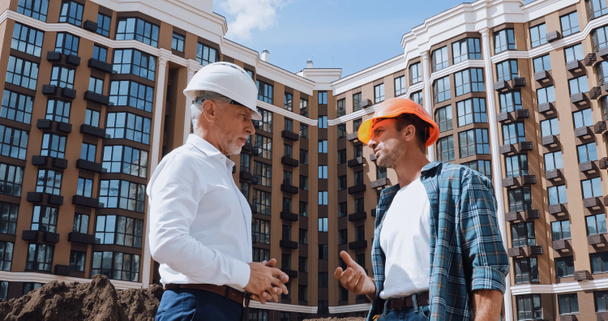low angle view of engineer and builder talking near new building - Photo, Image