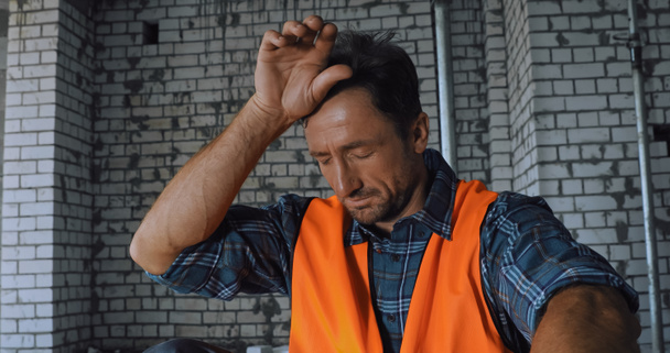 Tired builder touching forehead on construction site - Photo, Image