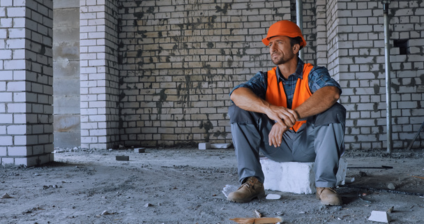 builder in safety vest and helmet looking away on construction site - Foto, Imagem