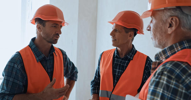 Builders in safety helmets talking on construction site - Photo, Image