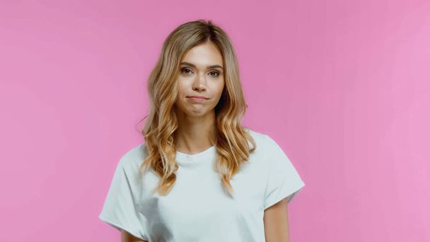displeased and blonde woman looking at camera isolated on pink - Фото, изображение