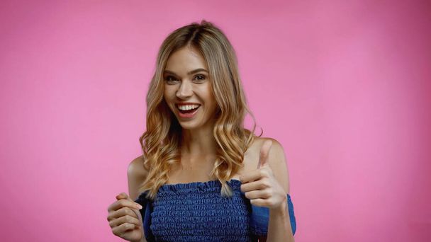 cheerful young woman showing thumb up on pink  - Photo, Image