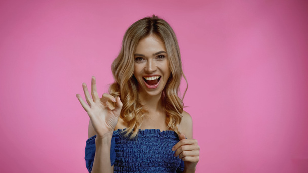 vrolijke jonge vrouw tonen oke teken op roze  - Foto, afbeelding