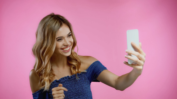 Ευτυχισμένη νεαρή γυναίκα που παίρνει selfie απομονωμένη σε ροζ  - Φωτογραφία, εικόνα
