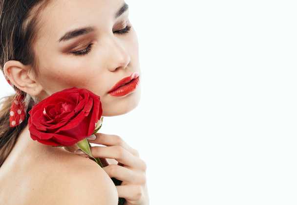Jovencita con hombros desnudos y una flor roja cerca de su cara - Foto, Imagen