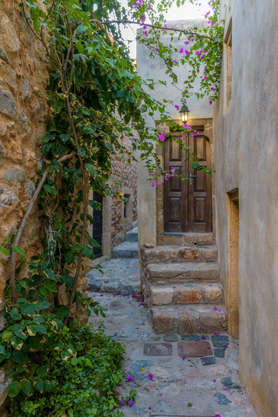Traditionele architectuur met smalle stenen straat en een kleurrijke bougainville in het middeleeuwse kasteel van Monemvasia, Lakonia, Peloponnesos, Griekenland. - Foto, afbeelding