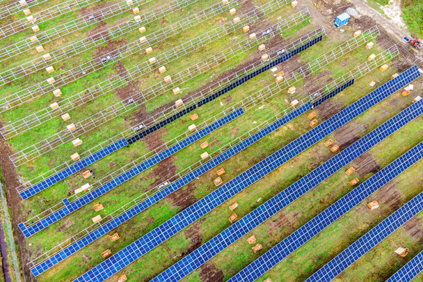 Vista aérea de la planta de energía solar en construcción en el campo verde. Montaje de paneles eléctricos para la producción de energía ecológica limpia. - Foto, imagen