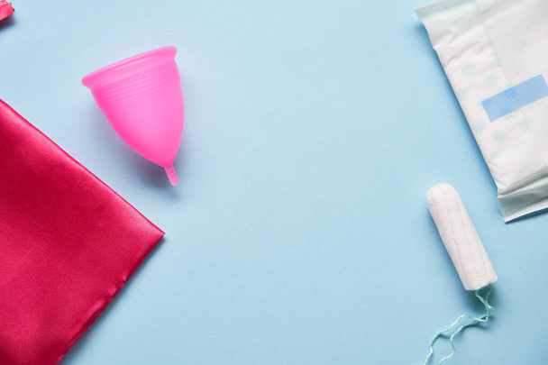 Pink menstrual cup and variuos of tampons on blue background - Foto, immagini