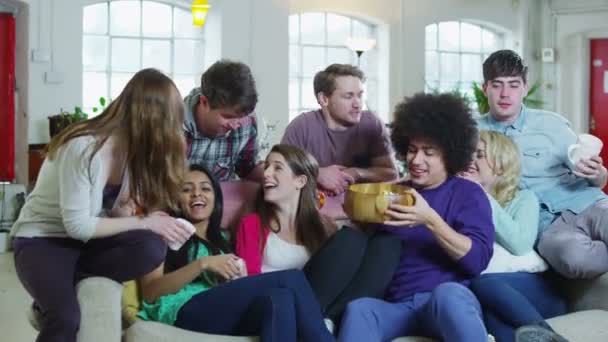 Onnellinen ryhmä ystäviä rentoutumassa sohvalla, syömässä popcornia ja katsomassa televisiota
 - Materiaali, video