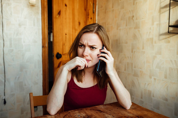 удивленная девушка слушает собеседника по телефону, держа голову рукой - Фото, изображение