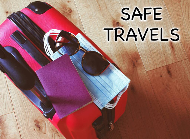 suitcase with sunglasses, passport and surgical mask, text "safe travels" - Foto, afbeelding