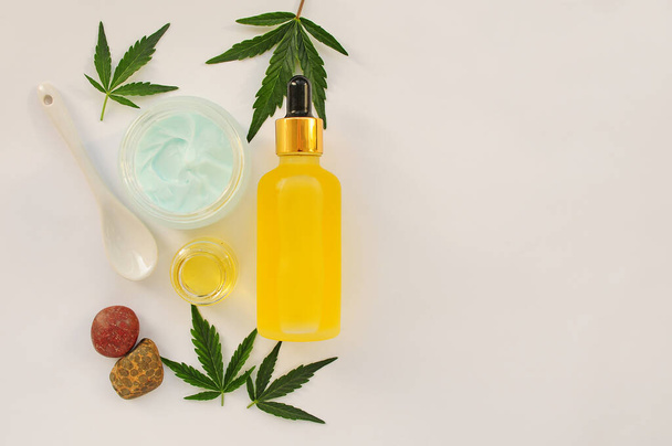Marijuana leaves, cbd oil, cosmetic cream. Fresh cannabis leaves close up, isolated on white background. Home relaxation, spa recreation, pastime therapy. Modern cosmetology. - Photo, Image