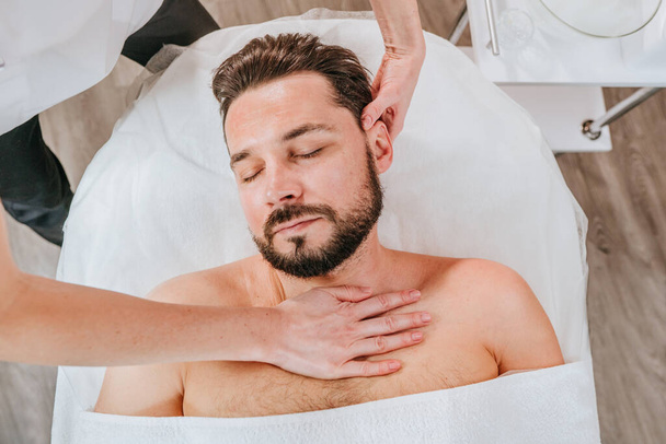 Эстетик или лицевик делает расслабляющий массаж лица мужчине - Фото, изображение