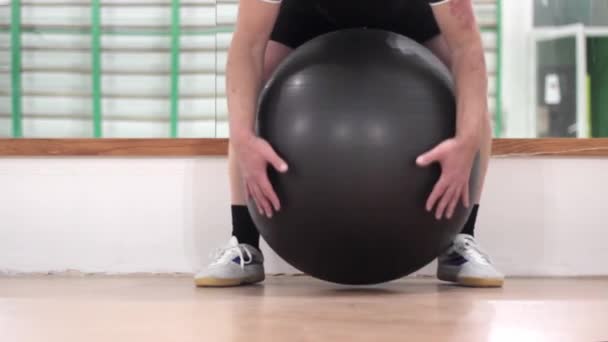 mężczyzna w klasie fitness z dużą nadmuchiwaną piłką - Materiał filmowy, wideo