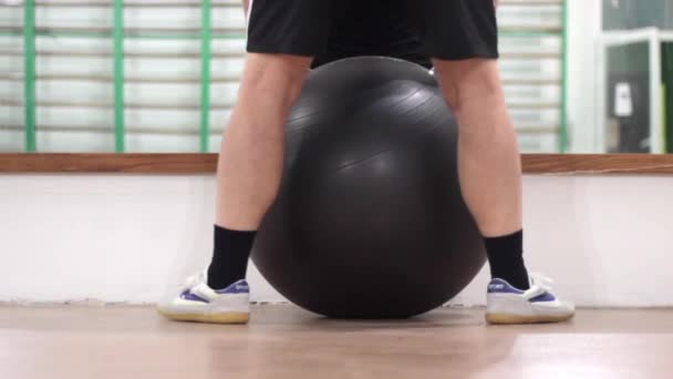 άνθρωπος σε τάξη φυσικής κατάστασης με μια μεγάλη φουσκωτή μπάλα - Πλάνα, βίντεο
