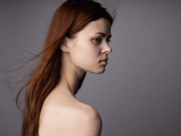 Zijaanzicht portret van vrouw met ontbloot schouders voor grijze achtergrond - Foto, afbeelding