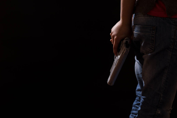 Дитина з неблагополучної родини ховає пістолет за спиною
.  - Фото, зображення