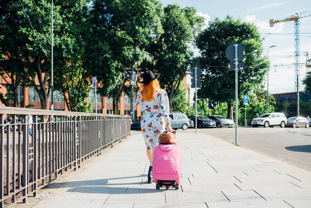 大人の生姜の頭の女性のバックビューアウトドア休暇のための旅行の荷物を運ぶ - 写真・画像