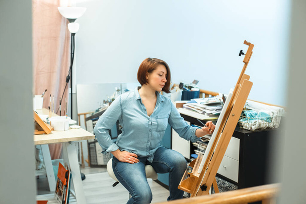 Συγκεντρωμένη μέση ηλικία Καυκάσια γυναίκα καλλιτέχνης σχέδιο με μολύβι σε καμβά στο σπίτι στούντιο τέχνης. Χόμπι δραστηριότητας τρόπου ζωής. Μοναδικό επάγγελμα. Ελεύθερος επαγγελματίας τέχνης ζωγραφίζει. Ψηφιακή αποτοξίνωση. - Φωτογραφία, εικόνα