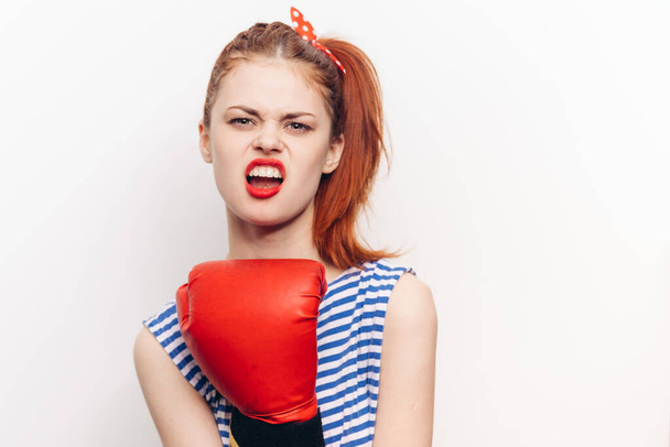 mujer en camiseta a rayas y en guantes de boxeo rojo deporte de agresión - Foto, Imagen