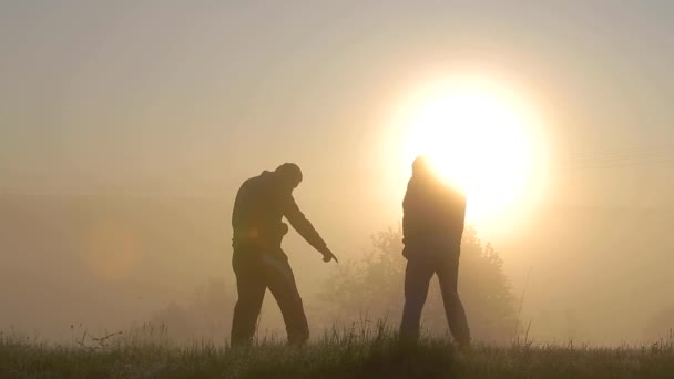 Silhouette sombre de deux hommes s'amusant à l'extérieur au lever du soleil. - Séquence, vidéo