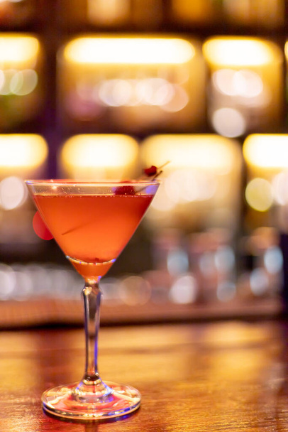 ヴィンテージバーの前にあるカクテルグラスにアルコールソーダと混合したストロベリージュース、背景イメージライトボケライトオレンジイエロー. - 写真・画像