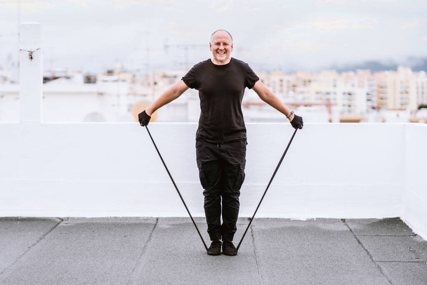Un uomo che si allena con una gomma sul tetto durante l'auto-reclusione causata da una pandemia - Foto, immagini