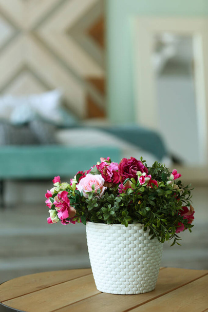modern hálószoba közeli töredék virágokkal vázában, kanapé és párnák a háttérben - Fotó, kép