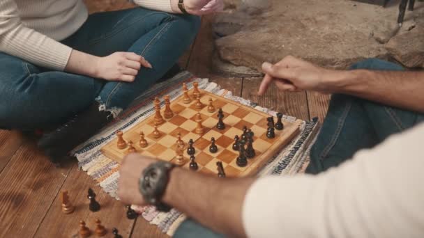 Chiudete. Giovane coppia che gioca a scacchi sul pavimento della casa accogliente - Filmati, video