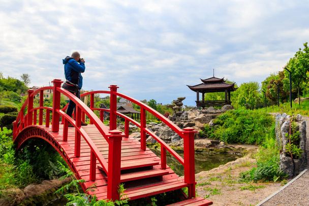 Fotografo di viaggio uomo con macchina fotografica professionale scattare foto del giardino giapponese - Foto, immagini