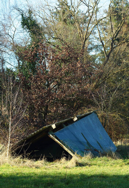 An old wooden cattle shelter with an asbestos roof collapsed. In a winter landscape in the countryside - Photo, Image