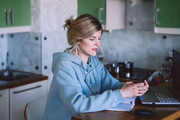 business woman looking at mobile phone while at home in the kitchen - Photo, Image