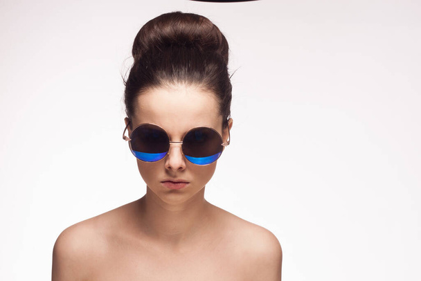 žena s holými rameny sluneční brýle móda oříznutý pohled světlo pozadí - Fotografie, Obrázek