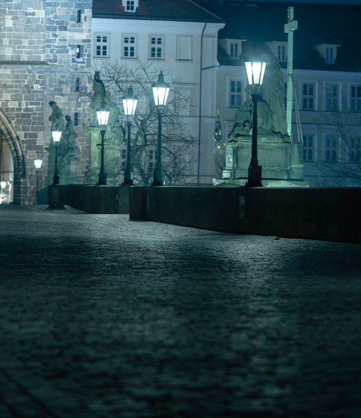 λάμπες στην άδεια Γέφυρα του Καρόλου στον ποταμό Vltava τη νύχτα και τον πύργο πέτρινης γέφυρας στο κέντρο της Πράγας - Φωτογραφία, εικόνα