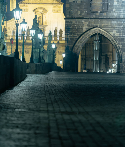lampy na prázdném Karlově mostě na Vltavě v noci a kamenná mostní věž v centru Prahy - Fotografie, Obrázek