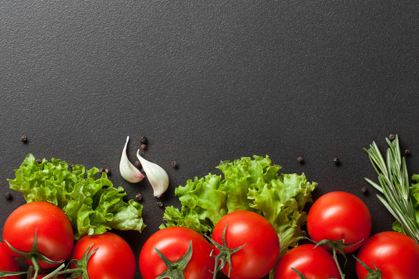 red tomatoes with green salad on black - Valokuva, kuva