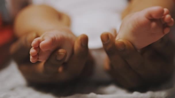 Acercaos, pies de bebé. El padre y el hijo se unen. Hombre afroamericano jugando con los pies pequeños de su bebé mulato - Metraje, vídeo