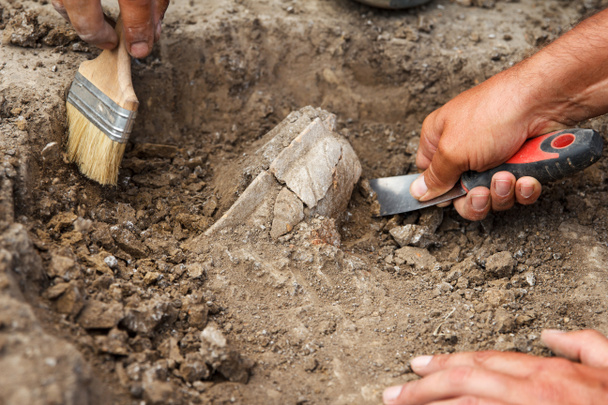 Arkeolojik kazılar, arkeologlar toprakta özel aletler bulunan antik bir kil kalıntısını kazıyorlar. - Fotoğraf, Görsel