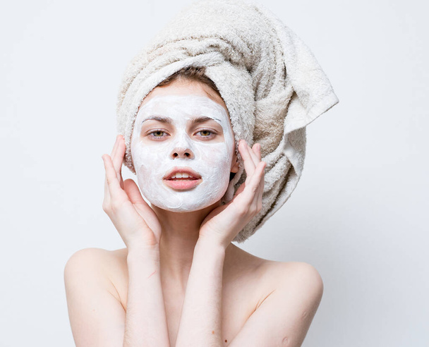Nainen kerma kasvoillaan pyyhe hänen päänsä ihon hoito - Valokuva, kuva
