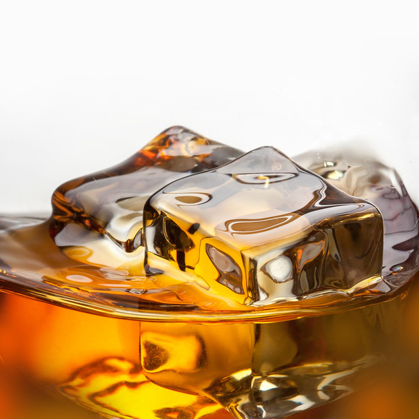 Splash of whiskey with ice in glass isolated on white background - Фото, изображение