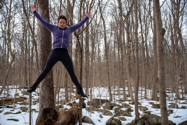 Jeune femme sportive joyeuse sautant dans les airs dans une forêt d'hiver - Photo, image