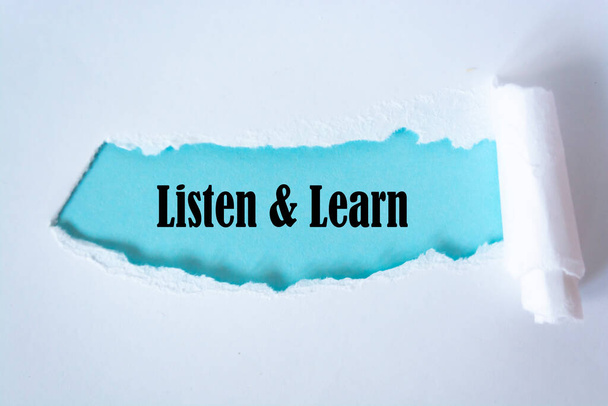 Zwrot "Słuchaj i ucz się" napisany pod podartym papierem. - Zdjęcie, obraz
